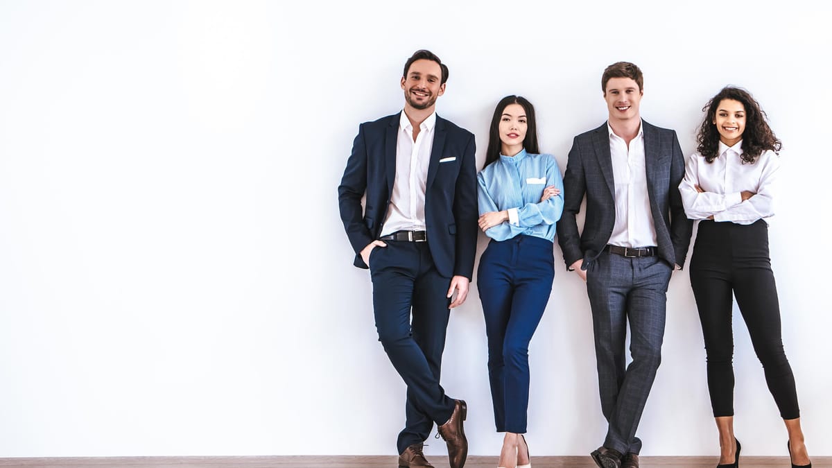 Four business professionals standing together against a plain wall