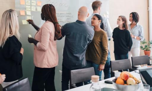 A large group collaborating at a whiteboard covered in notes